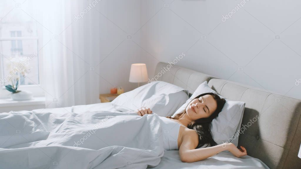 Attractive Brunette Cozily Sleeps in Her Bed while Early Morning Sunrays Illuminate Her. Warm, Cozy and Sweet Picture of Beauty Sleeping