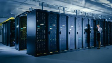Veri merkezi 'nde: kadın BT teknisyeni açık sunucu raf kabine önce standları, böylece Mainframe optimum Işlev düzeyinde çalışır bakım tanılama çalıştırmak için dizüstü bilgisayar kullanır.
