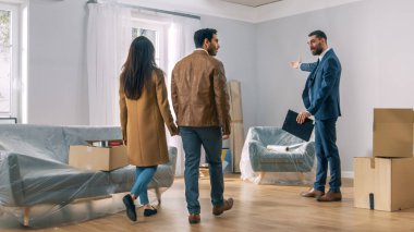Profesyonel gayrimenkul ajanı genç bir çift için parlak yeni daire gösterir. Başarılı genç çift ev sahibi olmaya hazır. Büyük pencerelerin bulunduğu geniş parlak ev.