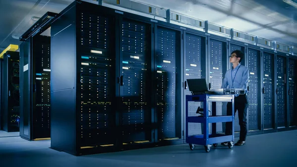 I det moderna data centret: IT-tekniker som utför underhåll och diagnostik. Knuffar vagn tillsammans Server rack, redo att installera ny maskinvara för planerad system uppdatering, utbyte av utrustning. — Stockfoto