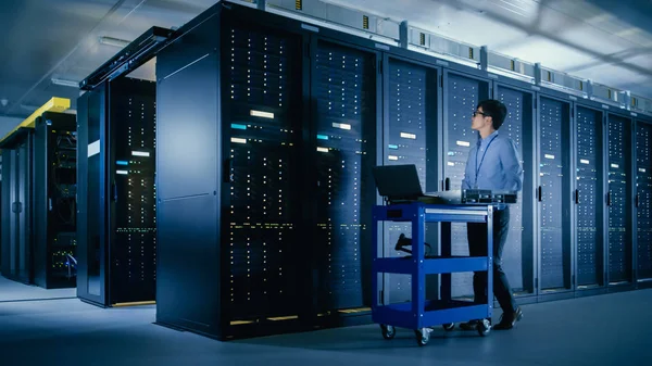 In the Modern Data Center: IT Engineer Doing Maintenance and Diagnostics. Empuja el carro junto con los bastidores del servidor, listo para instalar nuevo hardware para la actualización del sistema planificado, reemplazo del equipo . — Foto de Stock