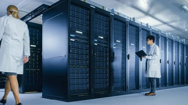 Veri Merkezi: erkek o teknisyen beyaz ceket giyen sunucu raf kabine yanında standları, bakım tanılama araçları çalıştırmak için dizüstü bilgisayar kullanır. Lab Coats 'un veri ile çalışmasını yapan insanlar.