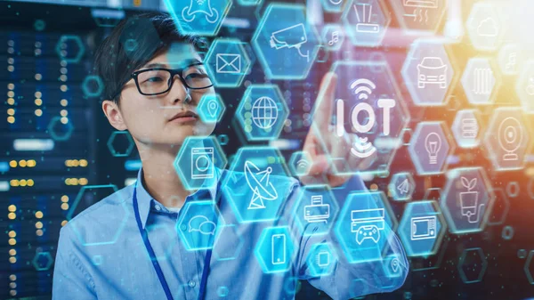 Fotografía de un ingeniero de TI asiático que trabaja en una sala de servidores del centro de datos. Concepto de Internet de las Cosas con diferentes iconos y símbolos ilustrativos de computadora en primer plano . —  Fotos de Stock