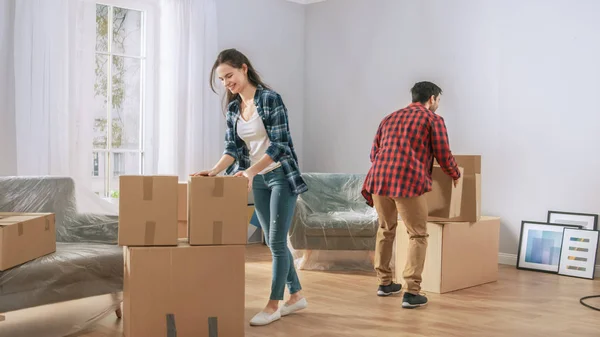 Feliz joven pareja que se muda a un nuevo apartamento, llevando cajas de cartón con cosas. Joven Novio y Novia Empezar a Vivir Juntos, Desempacar Cosas . — Foto de Stock