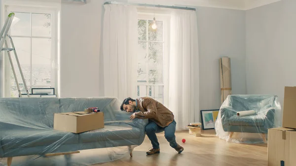 Ein sehr glücklicher Mann bezieht seine neue Wohnung, tanzt aufgeregt. Mann kaufte neues Zuhause bereit zum Auspacken von Kartons. — Stockfoto