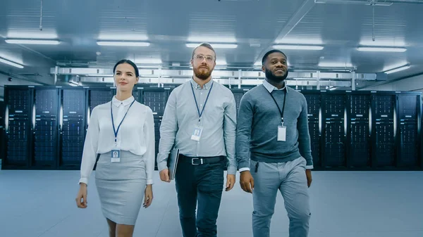 Professioneel team van Data Center IT-specialisten lopen weg van de werkende server kasten rack corridor met een laptop computer. Ze zijn gekleed slim. — Stockfoto