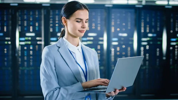 Female IT Specialist is Working on Laptop in Data Center Next to Server Racks. — Stock Photo, Image