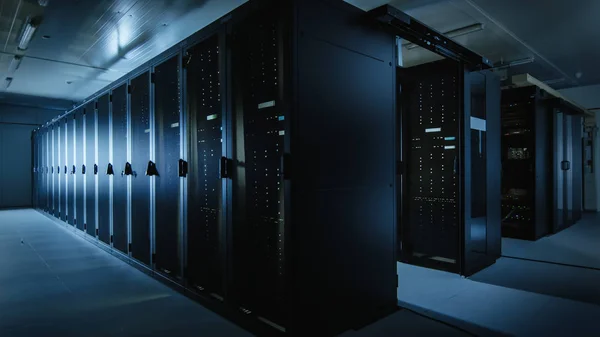 Tournage d'un centre de données fonctionnel avec des rangées de serveurs de rack. La clignotement des lumières LED et les ordinateurs fonctionnent. Lumière ambiante sombre . — Photo