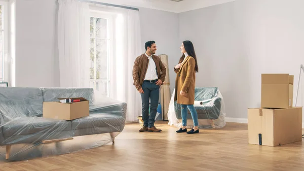 Happy and Excited Young Couple Look Around In Wonder at their Newly Purchased / Rented Apartment. Les belles personnes posent heureusement. Grande maison moderne lumineuse avec boîtes en carton prêtes à déballer . — Photo