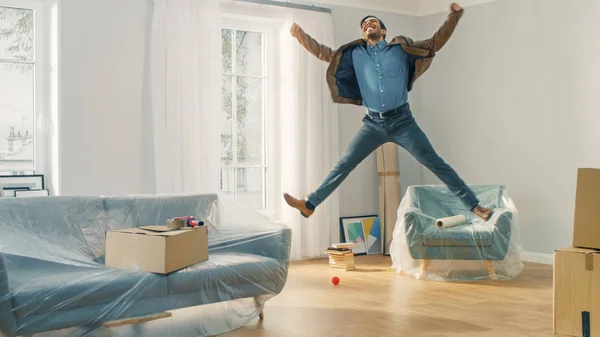 Very Happy Man Moves Into His New Apartment, Jumps Excited. Guy Purchased New Home Ready to Start Unpacking Cardboard Boxes. — Stock Photo, Image