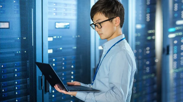 I det moderna data centret: IT-ingenjör stående bredvid Server rack skåp, gör trådlöst underhåll och diagnostik förfarande med en bärbar dator. — Stockfoto