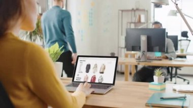Omuz Over: kadın çalışan online perakende alışveriş sitesi Through Browsed. Genç profesyoneller çeşitli ekip bilgisayarlarda çalışma ofis
