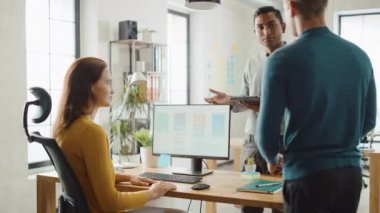 Üç mobil yazılım geliştiriciler çalışma masaüstü bilgisayar, onlar tartışmak Smartphone uygulama tasarım kullanım dokunmatik ekran dijital tablet. Profesyonel çalışma çeşitli ekibi ile modern şık ofis