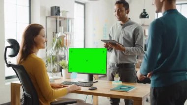 Üç başlangıç girişimciler çalışma masaüstü bilgisayar yeşil mock-up ekran ile, onlar proje tasarım tartışmak, dokunmatik ekran dijital tablet kullanın. Çeşitli profesyoneller ekibi ile modern şık ofis