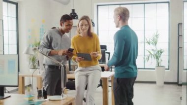 Ofiste: üç farklı başlangıç girişimciler proje hakkında toplantı ve tartışma var. Dokunmatik ekran dijital tablet ve akıllı telefon ekranları paylaşın. genç profesyoneller gülümseme ve şaka etrafında