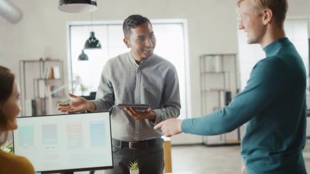 Im Büro: vielfältiges Team mobiler Softwareentwickler arbeitet am Desktop-Computer, diskutiert über Smartphone-Anwendungsdesign mit digitalem Tablet, feiert mit High Five nach Projekterfolg — Stockvideo