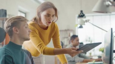 Yakışıklı profesyonel oturma onun Desk çalışma içinde laptop bilgisayar, genç güzel takım lideri verir tavsiyeler hakkında proje detayları. Genç profesyonellerin çeşitli ekibi çalışma ofis