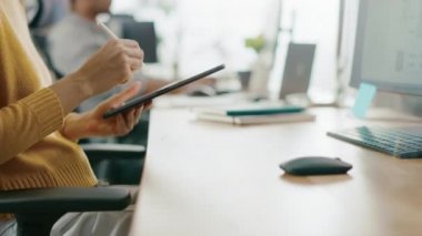 Yetenekli kadın Tasarımcısı masasında oturan o çizim, yazma ve dijital tablet bilgisayar ile kalem kullanma. Kalem ile Hands odaklanın. Genç profesyonellerin çeşitli ekibi çalışma parlak ofis
