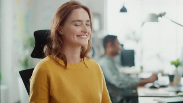 Portré gyönyörű fiatal nő, vörös hajú viselése sárga pulóver beszélgetések kollégája és menstruáció mosolygó a kamera. Sikeres nő dolgozó Bright sokszínű iroda — Stock videók