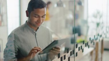 Yakışıklı profesyonel Hint adam portre dokunmatik ekran dijital tablet bilgisayar kullanır, önemli e-posta, Smiles charmingly yazar. Parlak farklı ofiste çalışan başarılı adam