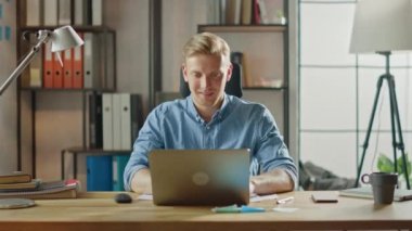 Ofisteki masasında oturan yakışıklı sarışın iş adamı dizüstü bilgisayarda çalışıyor. Yazılım Unicorn Startup Project üzerinde çalışan yaratıcı girişimci. Üniversite için Öğrenci Yazma Kağıdı