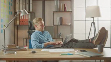 Yakışıklı Genç Girişimci Bacakları Masanın Üzerinde Dizüstü bilgisayarla Çalışıyor. Tasarımcı, Yazılım Unicorn Startup 'ı yaratmak için Not Defteri kullanır. Üniversite için Serin Öğrenci Yazma Kağıtları