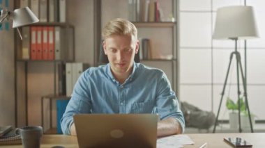 Yakışıklı Genç Girişimci Ofiste Çalışıyor Laptop Bilgisayarını Kapatıyor, Masadan Akıllı Telefonu Alıyor ve İşbırakıyor