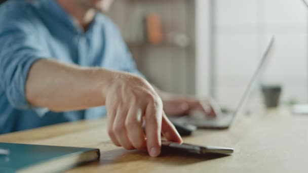 Businessman Sitting at His Desk Works on Desktop Computer in the Stylish Office, Picks up and Starts Menggunakan Smartphone, Uses Social Media App, Emailing Business Partners, Messaging. Fokus pada Tangan dan Telepon — Stok Video