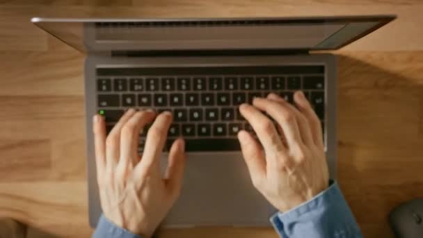 顶视图缩小镜头：商人坐在木桌工程在笔记本电脑在他的家庭办公室。他喝咖啡，类型，写作，冲浪互联网，创建和设计软件，网上购物 — 图库视频影像