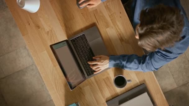 Top View Rotating Shot: Empresario sentado en el escritorio de madera funciona en un ordenador portátil en su Ministerio del Interior. Bebe café, tipos, escrituras, navega por Internet, crea y diseña software, compras en línea — Vídeo de stock