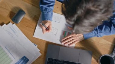 Ofiste Masasında Oturan İşadamı Dizüstü Bilgisayar Kullanır, Şirket Strateji Belgeleri ile Çalışır, Grafikleri Düzeltir, Grafik ve İstatistikleri Çizer. Üstten Görünüm Uzaklaştırma Döndürme Çekimi
