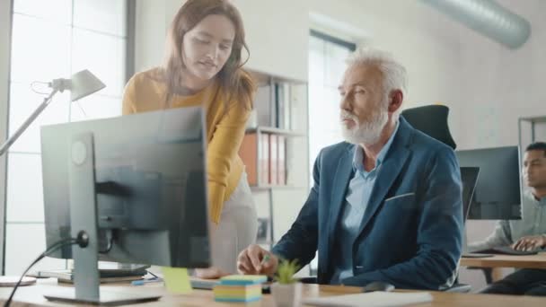 Handsome Middle Aged Creative Engineer Sitting at the Desk on Desktop Computer Has Discussion with Beautiful Female Project Manager. 우정적 인 동료들과 이야기를 나누며 해결책을 찾는 일 — 비디오