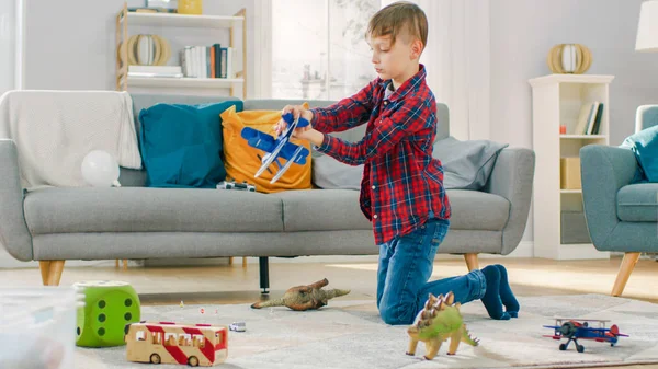 Zu Hause: Smart kleiner Junge spielt mit Spielzeugflugzeug. kleines Kind spielt auf einem Teppich im sonnigen Wohnzimmer. — Stockfoto