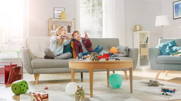 At Home: Cute Girl Playing in Video Game Console, Using Joystick Controller, Her Younger Brothe Cheers for Her. Happy Children Playing Videogames. — Stock Photo, Image