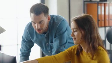 Bilgisayarda çalışan Güzel Kadın Ofis çalışanının Portresi, Yakışıklı Proje Yöneticisi Yanında Duruyor ve Müşteri Tecrübesi Yönetimi İçin İşakışının İyimserleştirilmesi Konusunda Tavsiye Veriyor