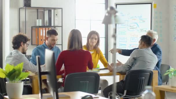 En la Sala de Reuniones Equipo de Empresarios de Startup que se sientan en la Mesa de Conferencias Discutir, Resolver Problemas, Usar Tablet, Ordenador Portátil, Compartir Documentos con Estadísticas, Gráficos . — Vídeos de Stock