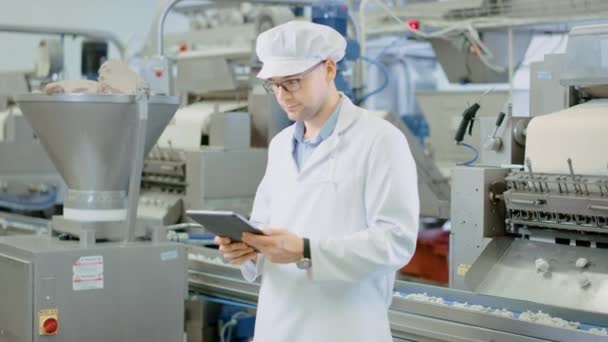 Young Male Quality Supervisor or Technician in Glasses is Working on a Food Factory. Employee Looks and Smiles at Camera. Expresses Success and Happiness. He Wears a White Sanitary Hat and Work Robe. — Stock Video