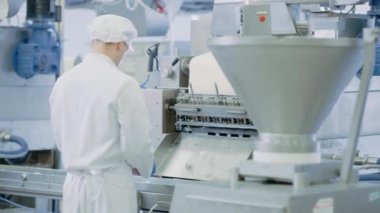 İki genç erkek yiyecek taşıma bandı çalışanı bir hamur köftesi fabrikasında çalışıyor. 