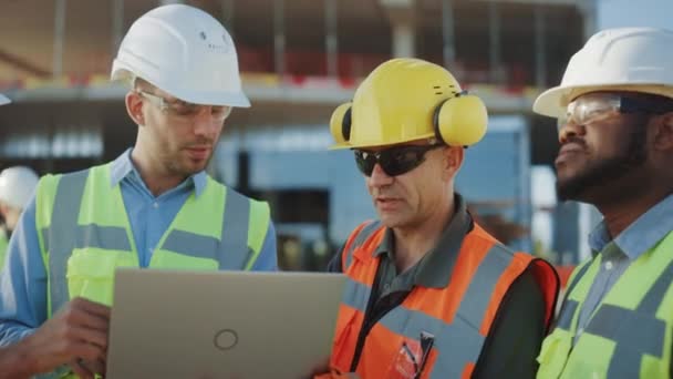 Diversi team di specialisti utilizzano il computer portatile sul cantiere. Progetto di Costruzione Immobiliare con Ingegnere Civile, Investitore Architettonico, Imprenditrice e Lavoratrice Piano di Discussione — Video Stock