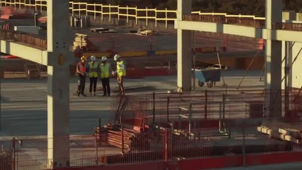 Vista aérea: Equipo diverso de especialistas inspecciona el sitio de construcción de encofrados comerciales, industriales y de rascacielos. Sobre el techo para el proyecto inmobiliario Ingeniero Civil, Inversor, Arquitecto y Trabajador Hablando — Vídeos de Stock