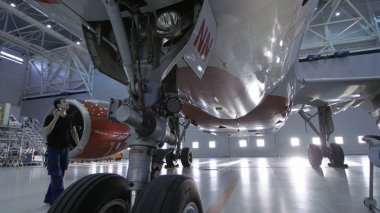 Bir Hangar uçak bakım mühendisi olarak / teknisyen / mekanik görsel olarak inceler uçak şasi ve gövde/gövde altında Bu yürüyüş.