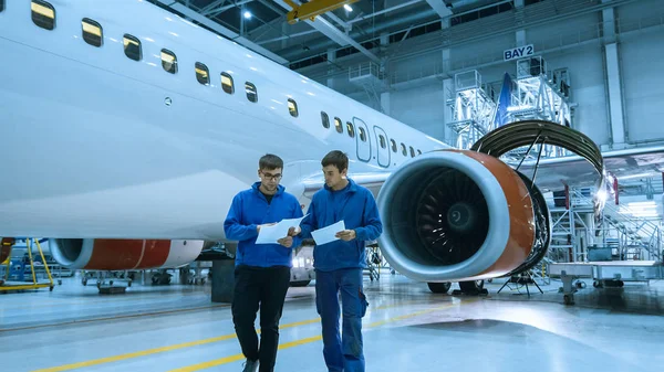 Underhåll flygmekaniker använder tablett framför flygplan stuga i en hangar. — Stockfoto