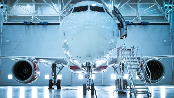 Lanzamiento ascendente de un avión nuevo de pie en un hangar de mantenimiento de aeronaves. La puerta del avión está abierta y la escalera está junto a ella . —  Fotos de Stock