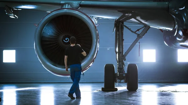 En un Hangar Ingeniero de Mantenimiento de Aeronaves / Técnico / Mecánico inspecciona con un motor a reacción de avión de linterna . — Foto de Stock