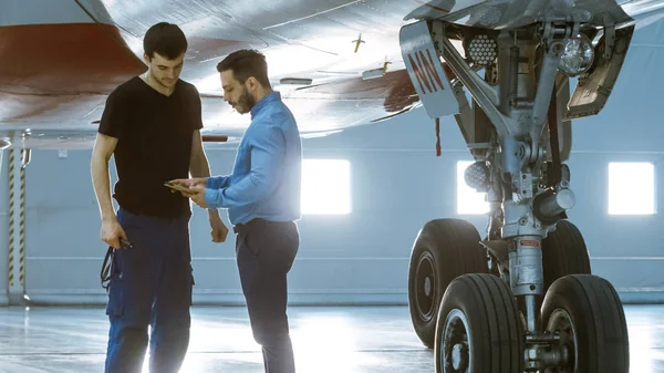 격납고 항공기 유지 보수 엔지니어 쇼 기술 데이터에서 비행기 기술자 태블릿 컴퓨터에. 그들은 깨끗 한 새로운 비행기 근처에 서. — 스톡 사진