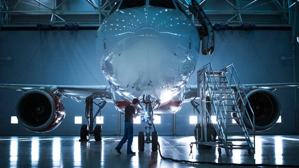 Novo avião em pé em um hangar de manutenção de aeronaves enquanto engenheiro / técnico / mecânico de manutenção de aeronaves entra na cabine via escada / rampa . — Fotografia de Stock
