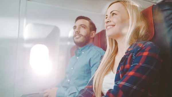Kaupallisella lentokoneella Komea latinomies kertoo hauska tarina hänen kaunis blondi tyttöystävä. Molemmat nauravat. He matkustavat New Airplane . — kuvapankkivalokuva