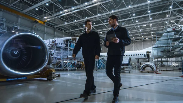 Équipe de mécaniciens d'entretien d'aéronefs se déplaçant dans le hangar. Ordinateur tablette Holding — Photo