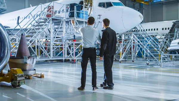 Vedlikeholdsarbeidere og ingeniører på luftfartøyer som har samtaler. Ser på flyet . – stockfoto