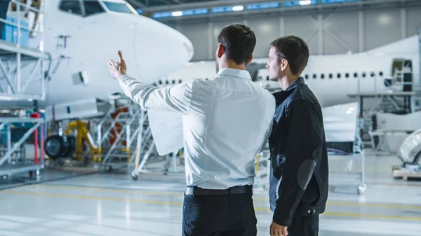 Trabalhador e Engenheiro de Manutenção de Aeronaves Conversando. Olhando para o avião . — Fotografia de Stock